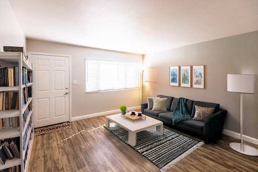 A living room with a black couch, a white coffee table, and a bookshelf filled with books.