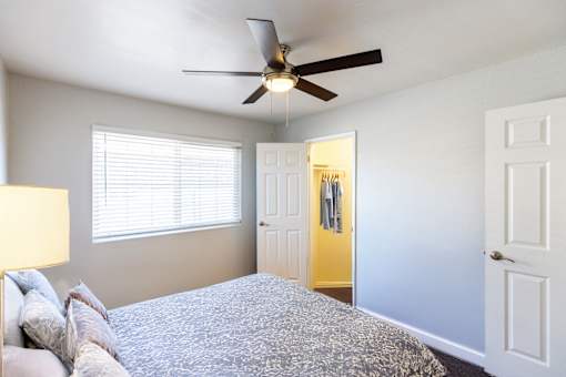 A bedroom with a bed, a ceiling fan, and a yellow door.