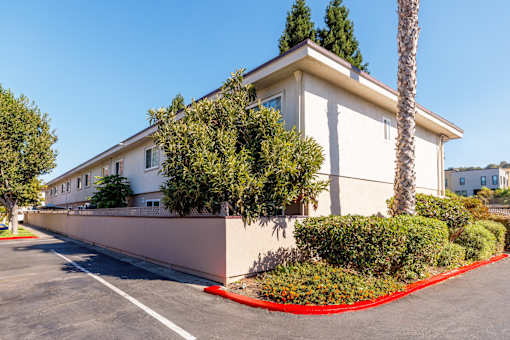A white building with a red border around the bushes.
