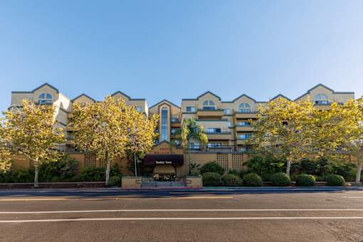 A row of apartment buildings with trees in front.