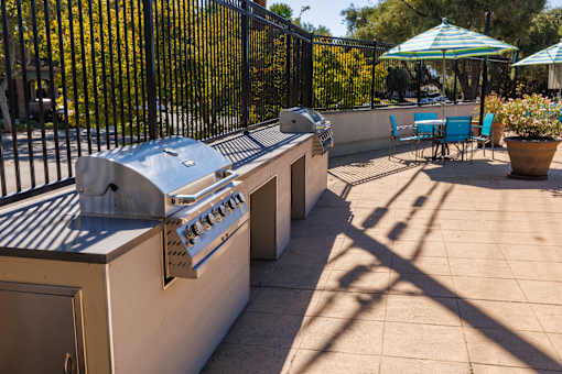 A patio with a grill and chairs.