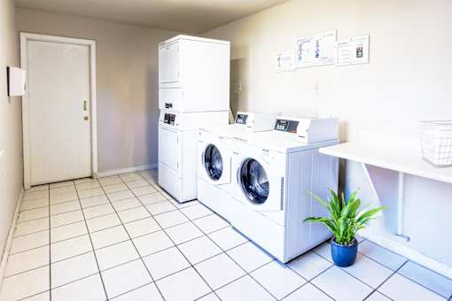A laundry room with a white tiled floor and a white door.