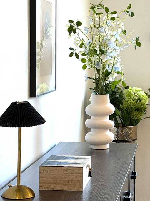A table with a lamp, a vase, and a book on it.