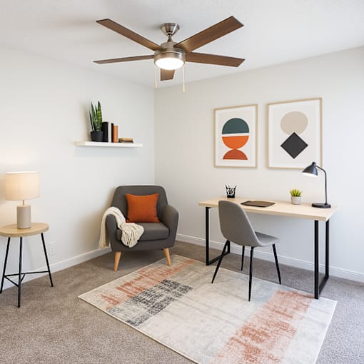 A room with a ceiling fan, a chair, a table, and a couch.
