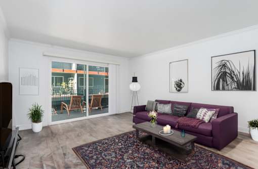 A living room with a purple couch and a rug.