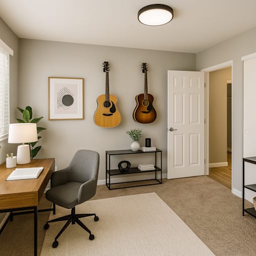 A room with a chair, a desk, and two guitars hanging on the wall.