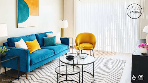 A living room with a blue couch, a yellow chair, and a coffee table.
