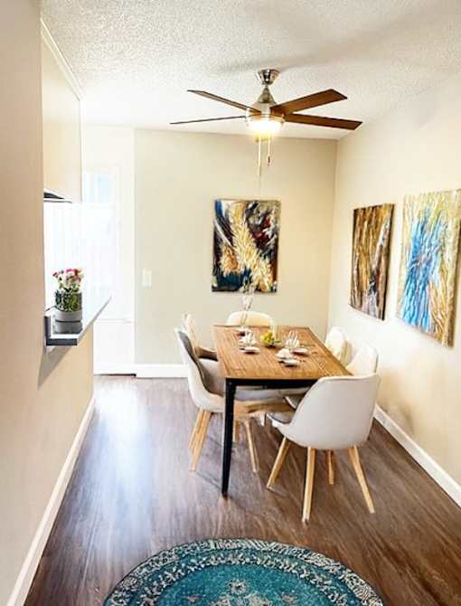 A dining room with a table set for two and a ceiling fan.
