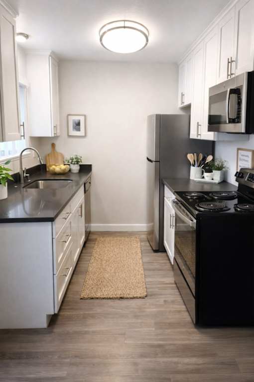 A kitchen with black countertops and white cabinets.