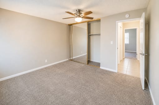 A room with a ceiling fan and carpeted floor.