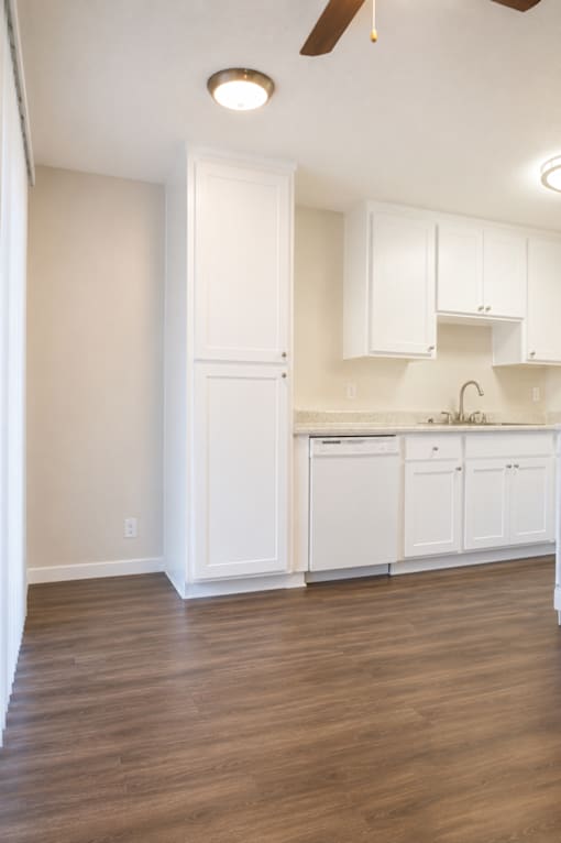 A kitchen with white cabinets and a ceiling fan.