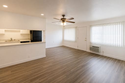 A spacious room with a ceiling fan and wooden flooring.