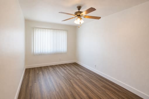 A room with a ceiling fan and wooden flooring.