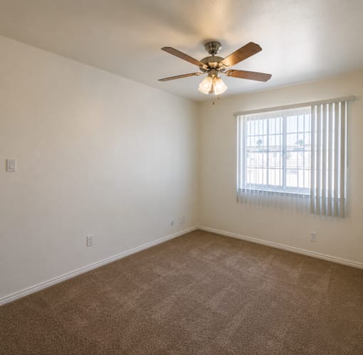 A room with a ceiling fan and carpeted floor.