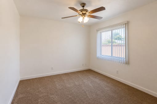 A room with a ceiling fan and carpeted floor.