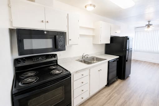 A black stove and microwave in a white kitchen.