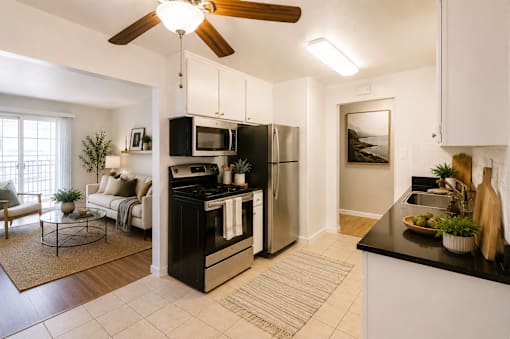A modern kitchen with black countertops and stainless steel appliances.