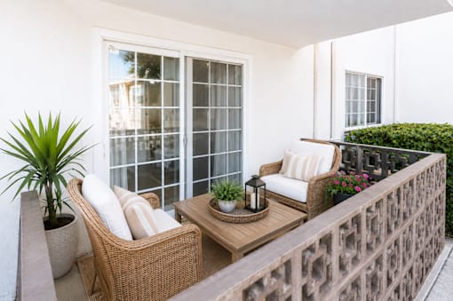 A patio with a wicker chair and table.