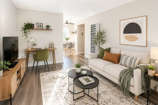 A living room with a white couch, a coffee table, and a television.