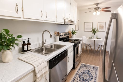 A kitchen with white cabinets and a blue rug on the floor.