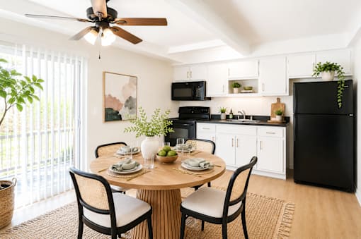 A black refrigerator is in a kitchen with a table and chairs.