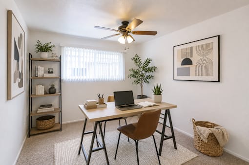 A room with a desk, chair, and a ceiling fan.