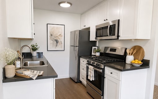 A modern kitchen with white cabinets and black countertops.