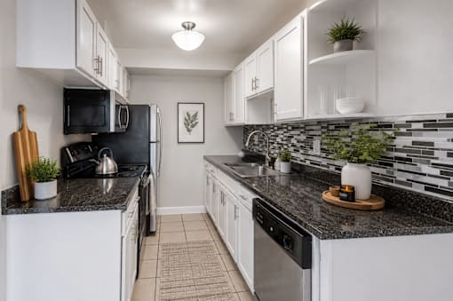 A kitchen with black countertops and white cabinets.