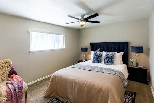 A bedroom with a bed, a chair, and a ceiling fan.