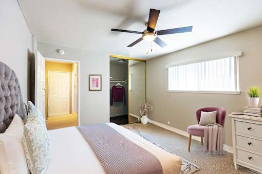 A bedroom with a bed, chair, and a ceiling fan.