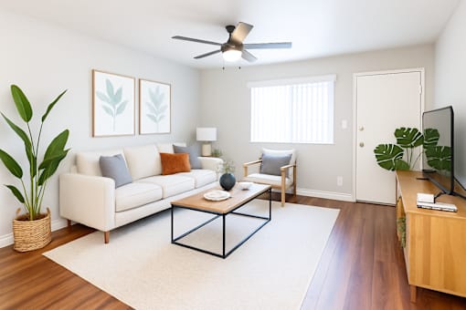 A living room with a white couch, a coffee table, and a ceiling fan.