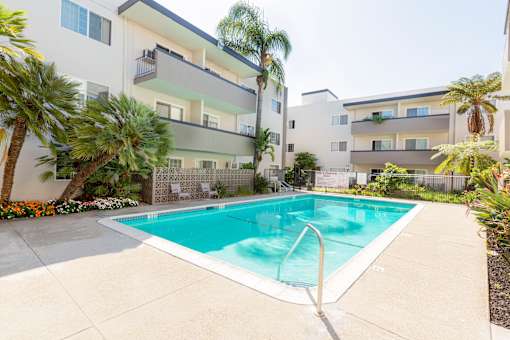 A swimming pool in front of a white apartment building.