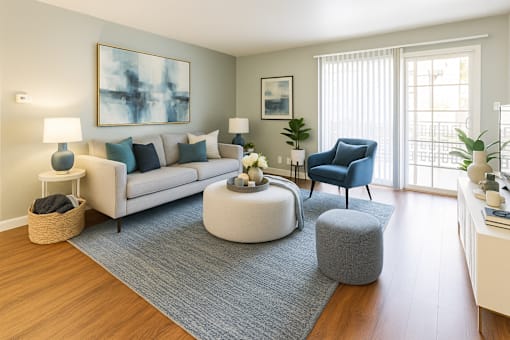 A living room with a white couch, a blue chair, and a grey ottoman.