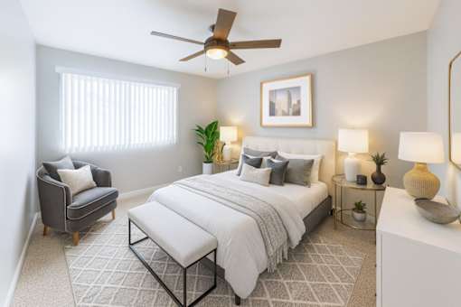 A bedroom with a large bed, a chair, and a ceiling fan.