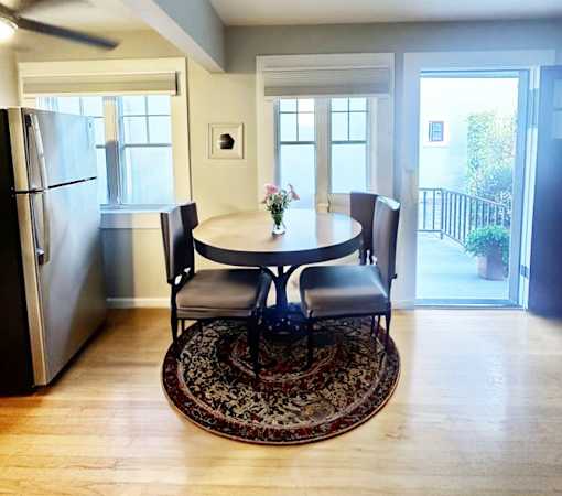 A dining room with a table and chairs and a refrigerator.