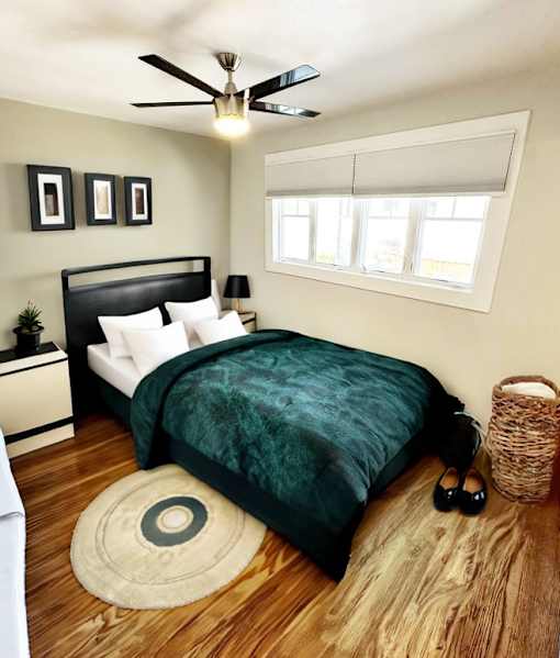 A bedroom with a bed, a ceiling fan, and a window.