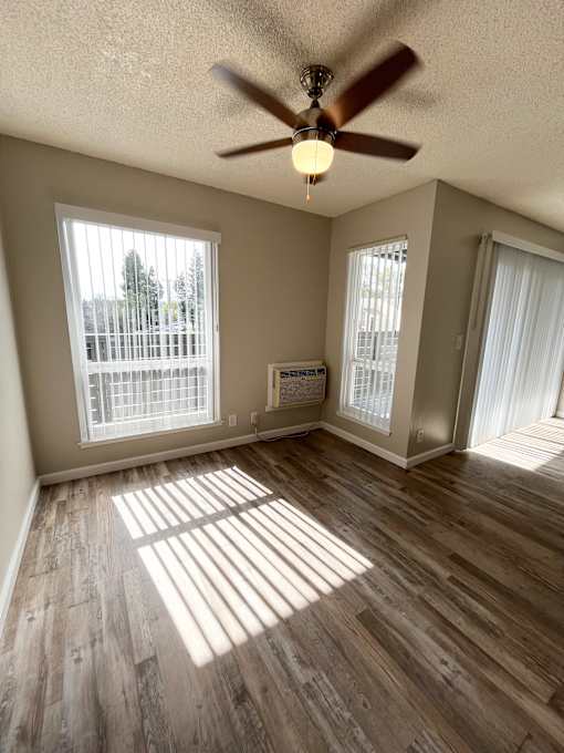 A room with a ceiling fan and wooden flooring.