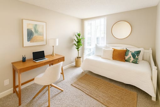 A room with a desk, chair, and bed.