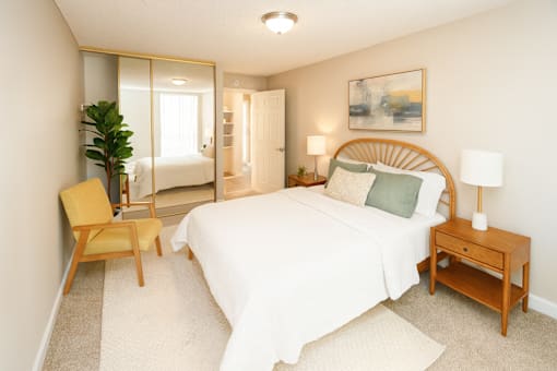 A bedroom with a large bed, a chair, and a painting on the wall.