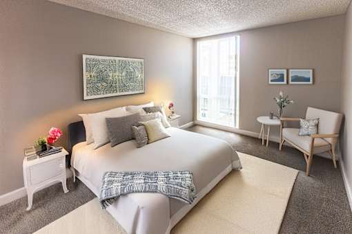 A bedroom with a large bed, a chair, and a painting on the wall.