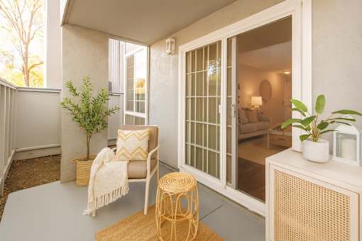 A patio with a chair, table, and potted plants.