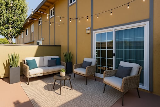A patio with a sofa, two chairs and a table with a plant on it.