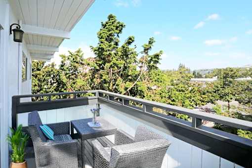 A balcony with a table and chairs overlooking a lush green landscape.
