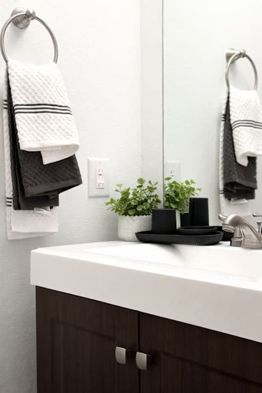 A bathroom with a white sink and towels hanging on the wall.