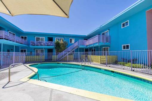 A blue building with a pool in front.