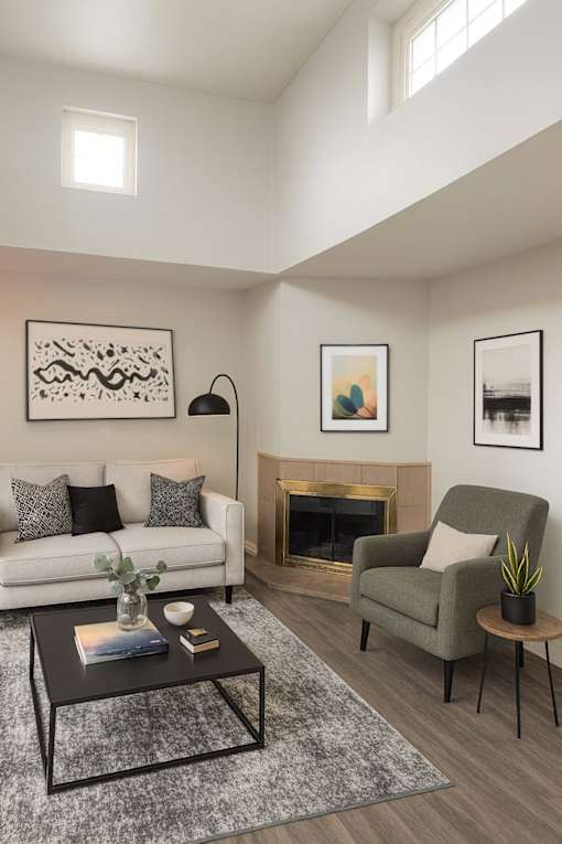 A living room with a white couch, a green armchair, a coffee table, and a fireplace.