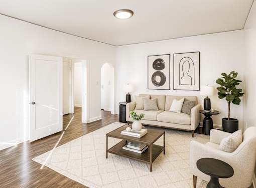 A living room with a white couch, a coffee table, and a plant.