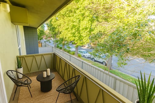 A balcony with a table and chairs overlooking a street.