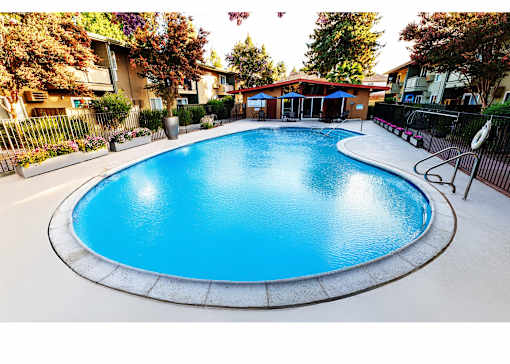 A blue swimming pool surrounded by a fence and trees.