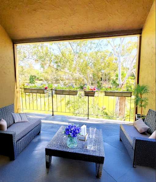 A patio with a table and chairs overlooking a tree-filled yard.